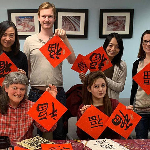 HSSPA members holding squares of red paper decorated with the Chinese character in black calligraphy, "福" (Fú).